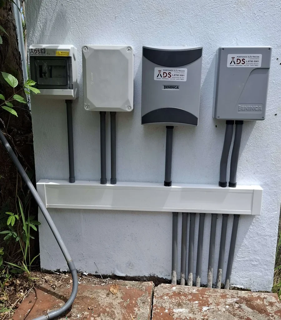 Cuatro gabinetes eléctricos Beninca alineados en muro blanco con canalización ordenada y calcomanías de Automáticas DS.