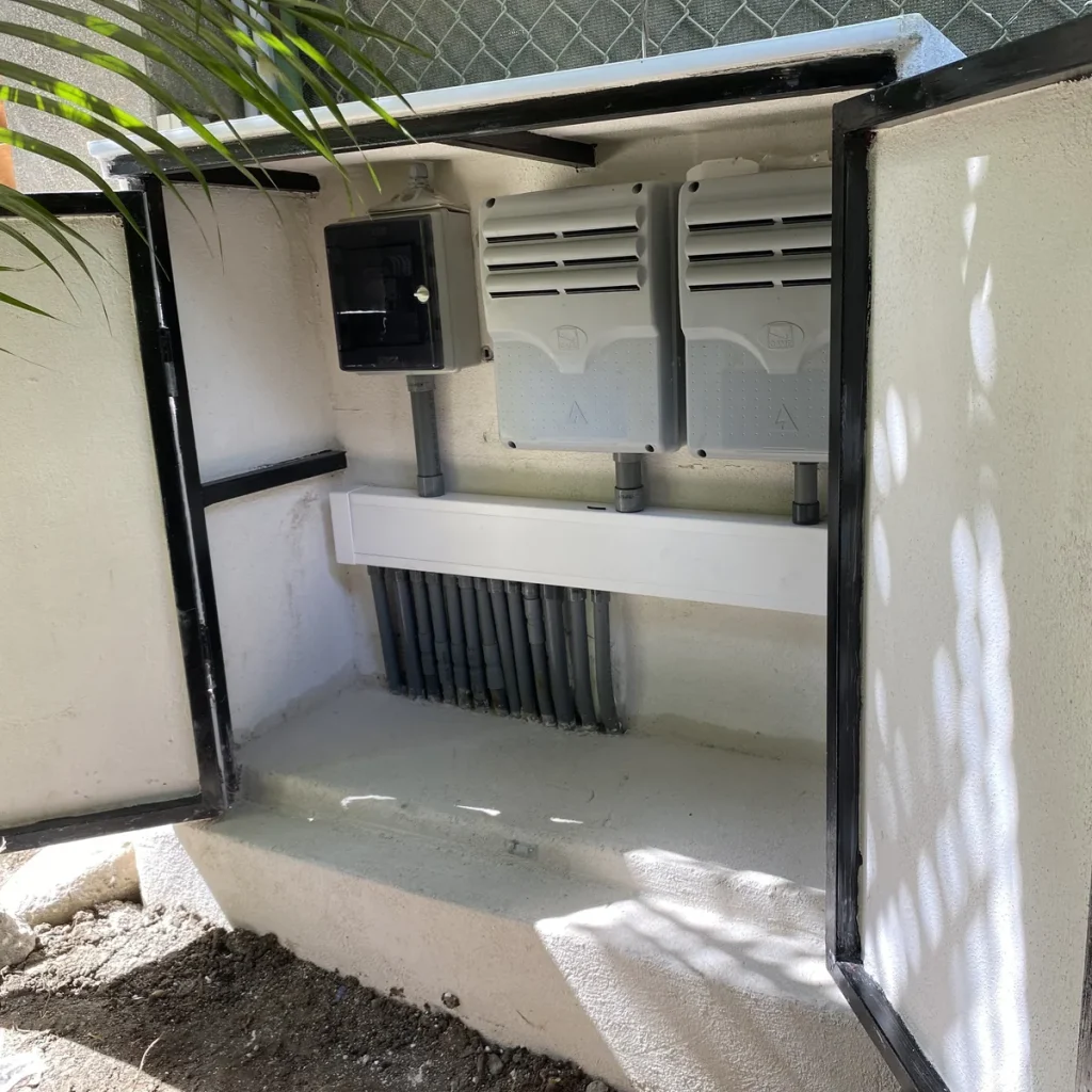 Gabinete exterior blanco abierto con centralitas, canalización y cableado organizado para automatización.